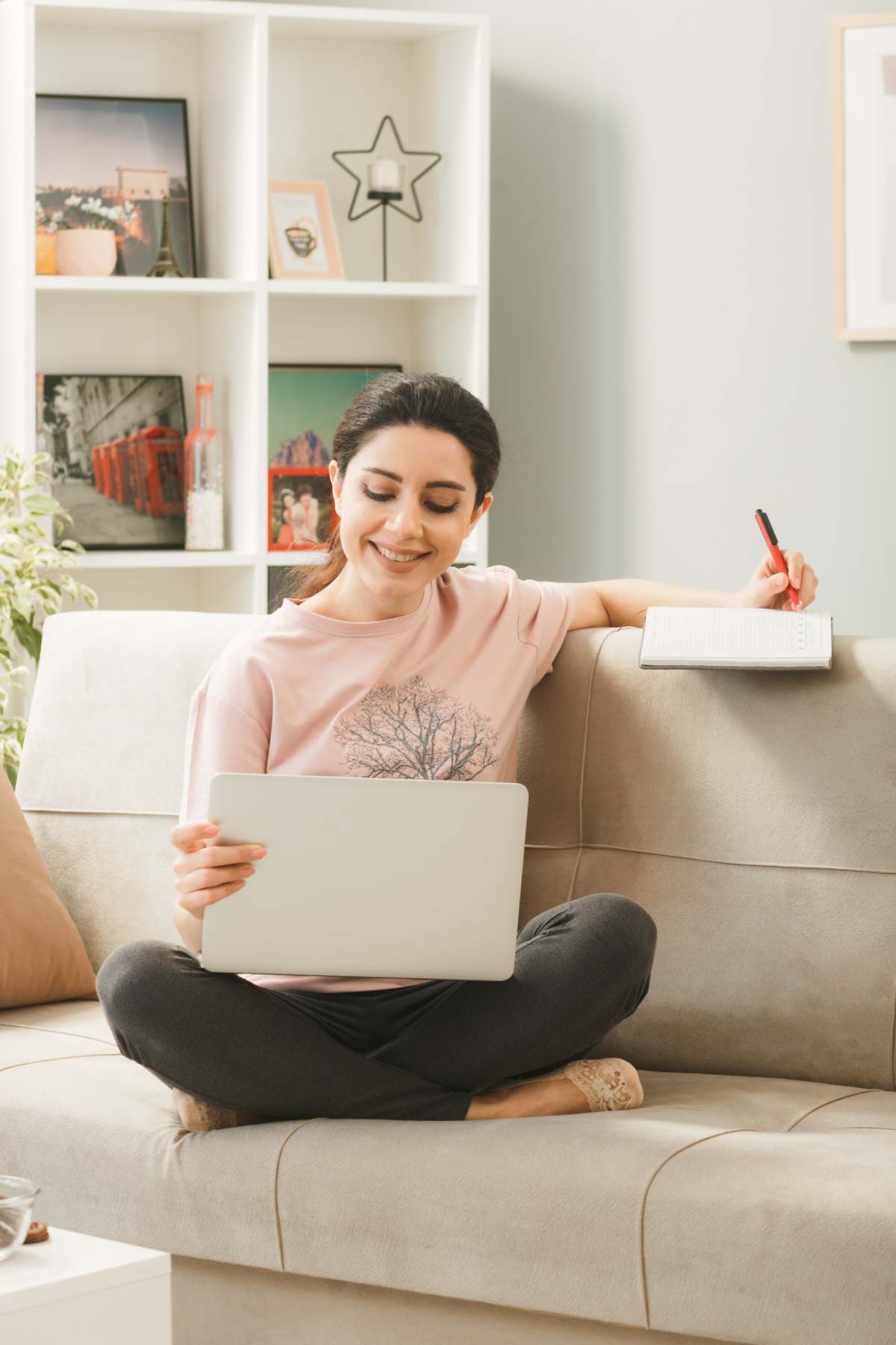 young-woman-sitting-sofa-coffee-table-holding-used-laptop-writes-book-living-room